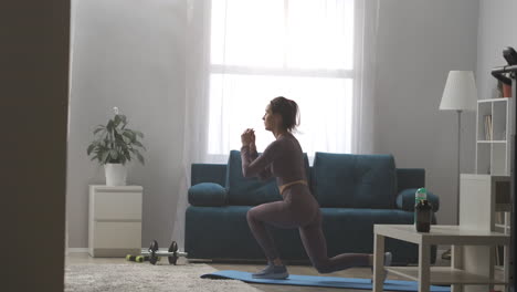 athletic-woman-is-squatting-and-jumping-in-living-room-of-modern-apartment-home-fitness-training-full-length-shot-slender-female-figure
